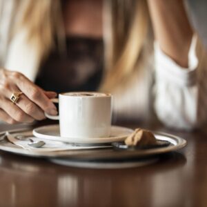 žena drži šalicu kave za stolom u mirnom jutarnjem trenutku, simbol svakodnevice i razmišljanja u četrdesetima